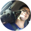 Homem de óculos, sorri com seu cachorro deitado no seu ombro.